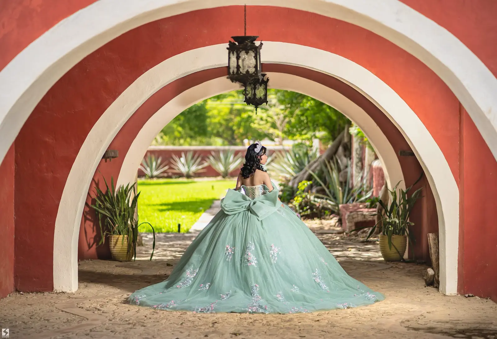 Quinceañera con vestido verde menta en los arcos rojos de la hacienda