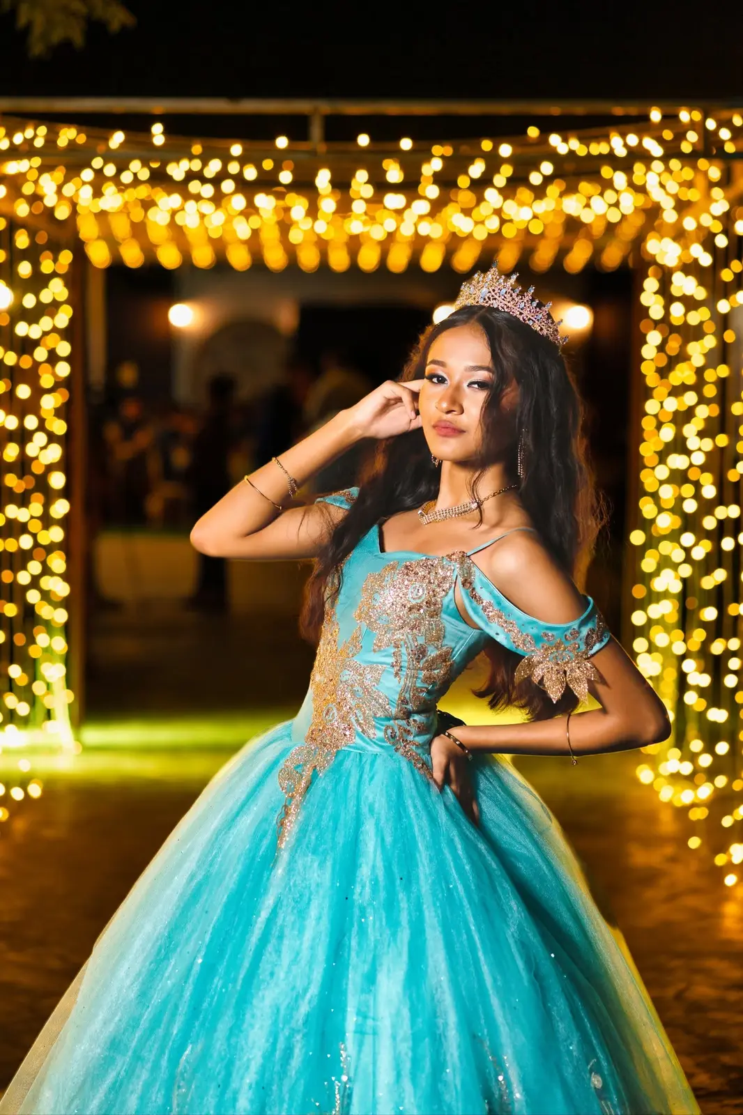 Quinceañera con vestido turquesa entre luces